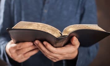 Hands holding an open Bible